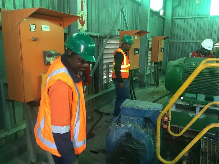Técnicos con chalecos reflectantes junto a motores en Jwaneng